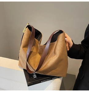 Macro detail of brown suede hobo bag with dark leather strap and golden buckle