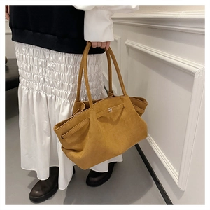 Dettaglio della borsa tote in pelle scamosciata giallo senape indossata da una modella