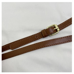 Dettaglio della tracolla in pelle marrone con fibbia dorata e cuciture di precisione