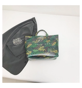 Detail of a black tote bag featuring vibrant tropical leaf prints and white text