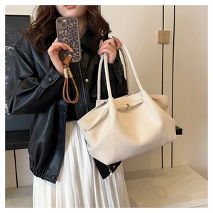 Dettaglio della borsa tote in pelle scamosciata crema con cinturini e fibbie dorate