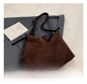 Close-up of a minimalist dark brown suede tote bag with V-cut design and leather strap