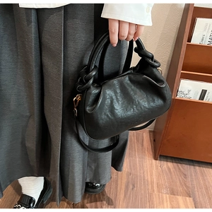 Détail du sac nuage noir avec plis texturés et poignée nouée épaisse pour femmes