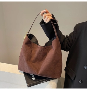 Detail of dark brown suede hobo bag featuring side gold hardware and long shoulder strap