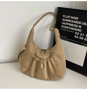Detail of camel suede shoulder bag with pleated pocket and brand embossing on the base