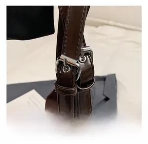 Detail of dark brown leather tote bag showing adjustable shoulder strap with silver buckles