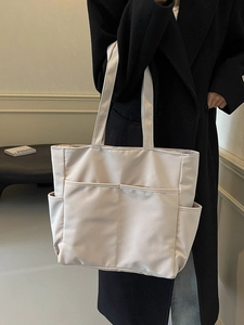 Sac fourre-tout minimaliste en nylon beige avec plusieurs poches porté par un mannequin