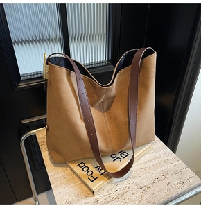Macro shot of minimalist tan suede bucket bag showing fine texture and leather strap