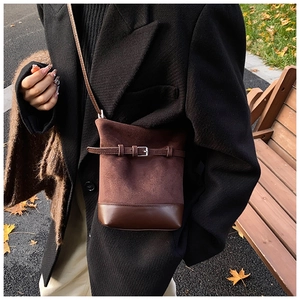 Détail du sac seau en daim marron avec boucle de ceinture pour un style automnal chic