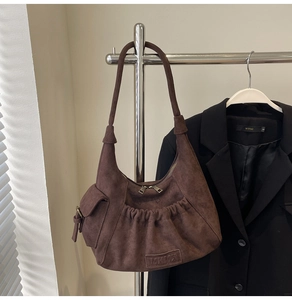 Detail of brown suede hobo bag with MKMX leather label and drawstring pocket design