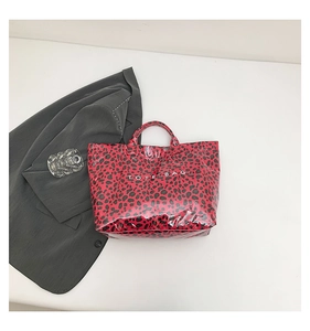 Flat lay of a red leopard print tote bag with glossy finish and large text logo