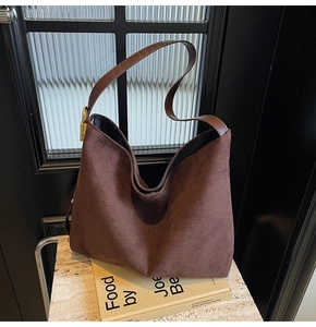 Close-up of brown suede bucket bag featuring a wide strap and golden adjustment buckle