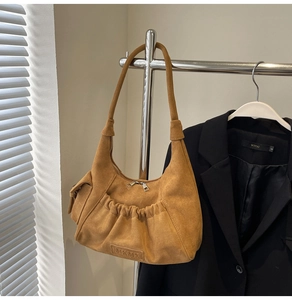 Detail showing brown suede texture, leather folds, and dual metal zipper on hobo bag
