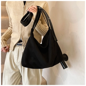 Detail of a large matte black tote bag with multiple thin shoulder straps for women