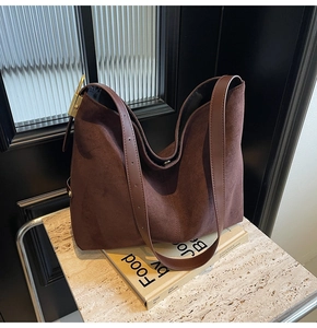 Detail of coffee brown suede hobo bag with leather strap and gold buckle on marble