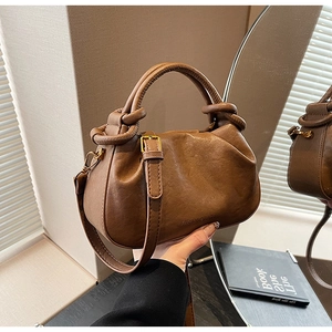 Dettaglio di una borsa marrone a pieghe con manico a nodo e fibbia in metallo regolabile