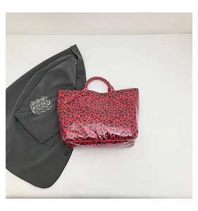 Detail of red leopard print tote bag with glossy finish and dual top handles