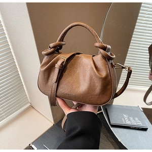 Dettaglio della borsa in pelle marrone scuro con design a pieghe e hardware dorato