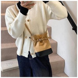 Détail du sac seau en daim kaki avec patchwork en cuir noir et boucle métallique élégante