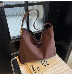 Close-up of dark brown suede hobo bag featuring a gold square buckle and magnetic closure