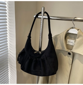 Detail of black suede tote bag with multi-pocket design and double metal zippers