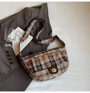 Detail shot of vintage plaid saddle bag with diamond quilting and gold twist-lock closure
