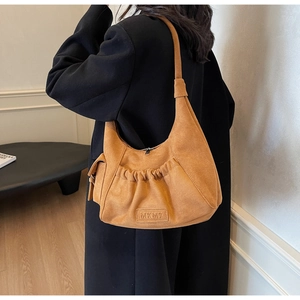 Detail of vintage mustard suede hobo bag featuring MKMX logo and pleated pocket texture