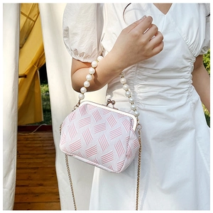 Detail of pink and white tweed mini bag featuring pearl handle and gold chain strap