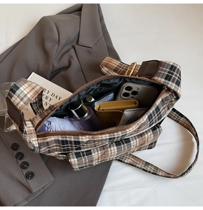 Detail view of the large capacity interior of a brown plaid wool underarm shoulder bag