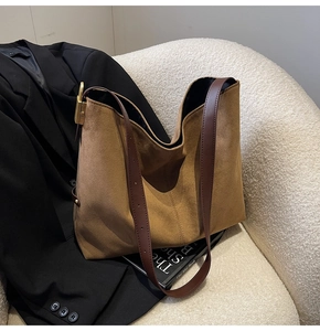 Close-up of brown suede tote bag with leather strap and golden hardware details