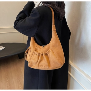 Detail view of the stylish camel suede hobo bag styled with a long black winter coat