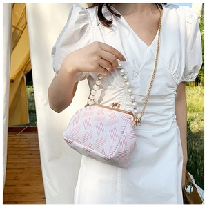 Detail of pink and white jacquard fabric texture with pearl handle and golden chain