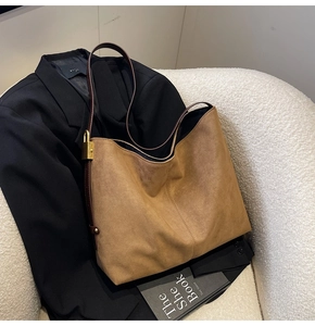 Close-up of brown suede bucket bag featuring elegant gold lock hardware and a long strap