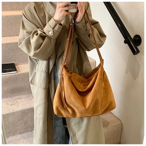 Detail of soft brown suede hobo bag with dual shoulder straps shown on a model
