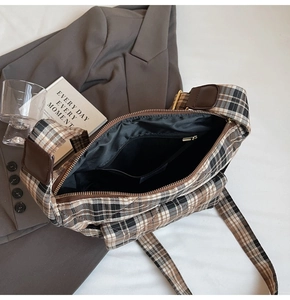 Detail shot of the interior zipper pocket and dark lining inside the plaid crossbody bag