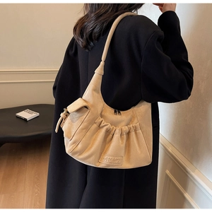 Chic beige suede moon bag with ruffled design and leather logo patch on a model
