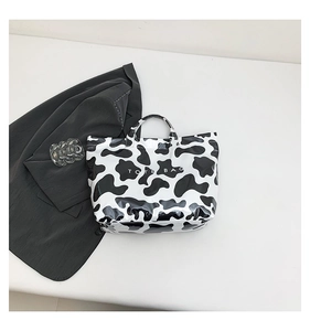 Close-up of a glossy cow print tote bag with black and white texture and tote lettering