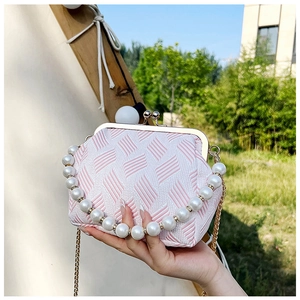 Detail showing pearl handle and gold chain strap on pink textured crossbody bag