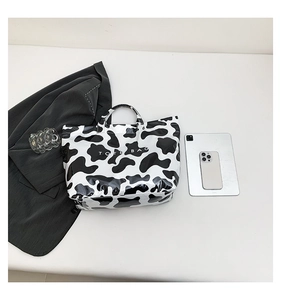 Flat lay of cow print glossy leather tote bag with large capacity and flat white background