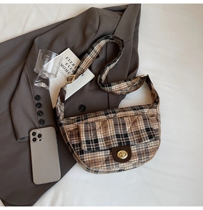 Detail of vintage plaid underarm bag with metal twist lock on a wool blazer