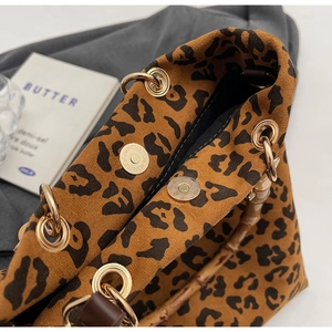 Dettaglio borsa scamosciata leopardata con manico in bambù e chiusura magnetica dorata