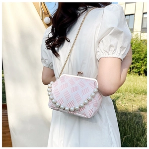 Detail of pink and white tweed frame bag with large pearl handle and gold chain strap