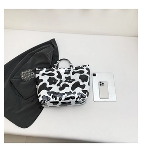 Close-up of large cow print tote bag showing black and white animal pattern texture