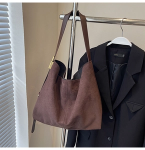 Detail of vintage brown suede tote bag featuring a gold buckle and adjustable strap