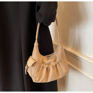 Detail view of khaki suede hobo bag featuring pleated front pocket and side flap compartment