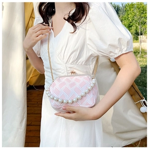 Detailed close-up of pink and white woven bag with pearl handle and golden kiss-lock closure