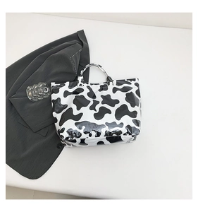 Detailed top view of a glossy black and white cow print tote bag with waterproof texture