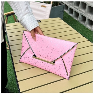 Gros plan sur la pochette enveloppe rose avec paillettes étoiles et fermoir doré