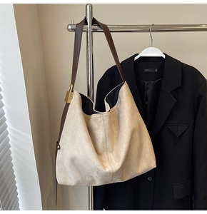 Detail of contrast brown leather strap and gold square buckle on suede shoulder bag