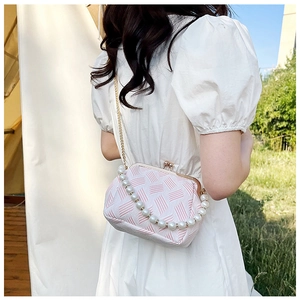Detail of pink and white woven bag with pearl handle and gold metal clasp closure